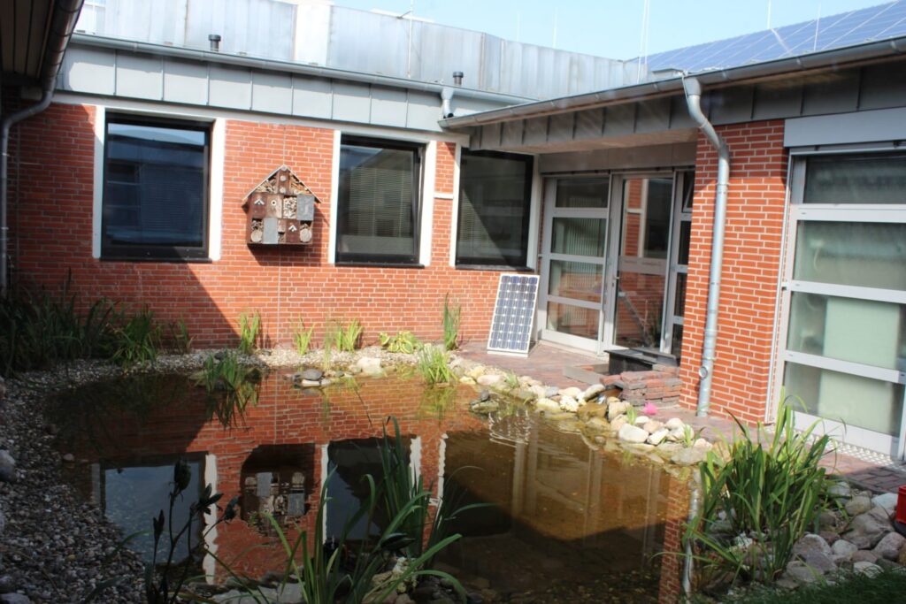 Innenhof der Schule mit Teich, Insektenhotel und Solarmodul